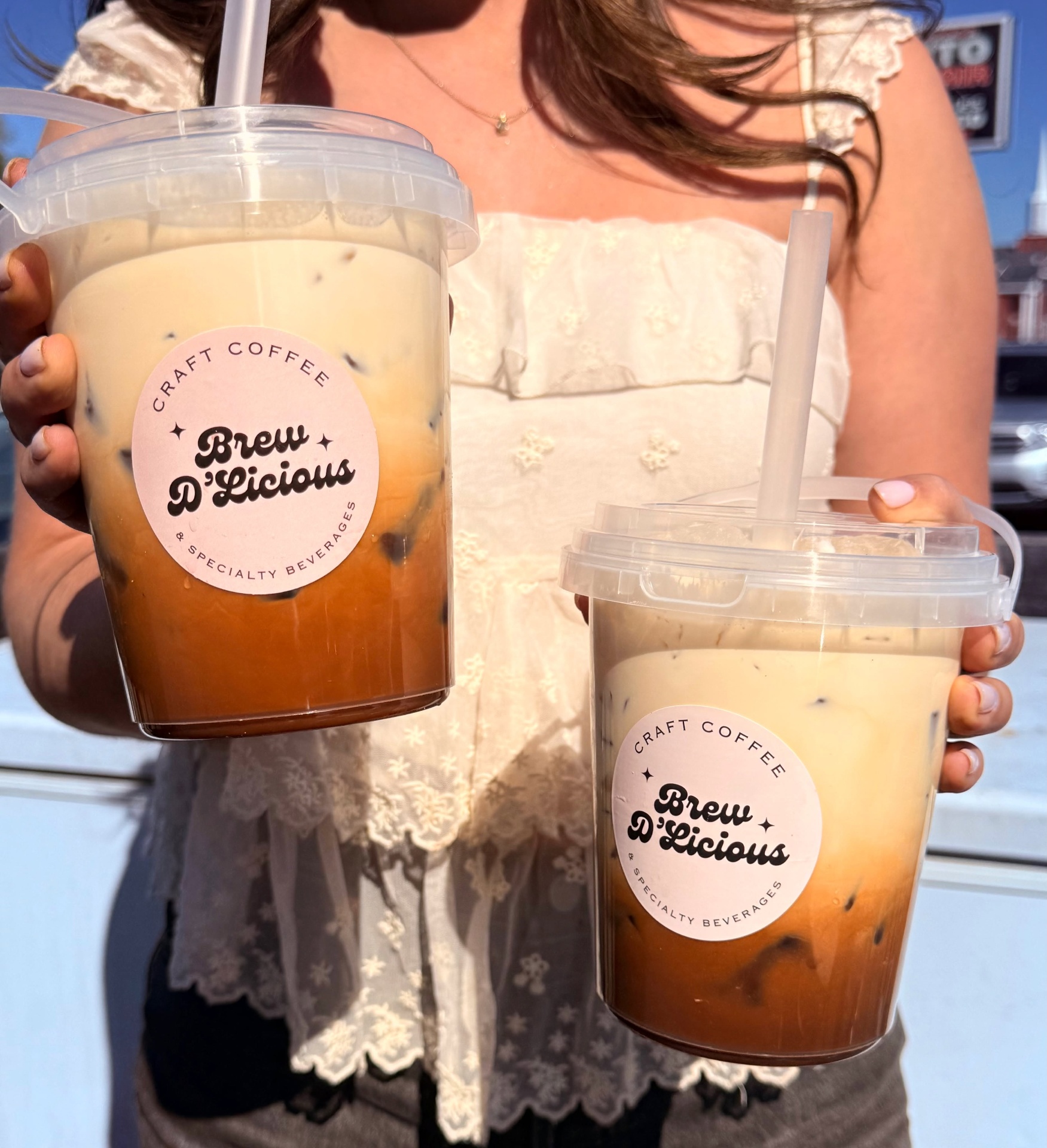 Two iced Brew D'Licious craft coffees held at the window